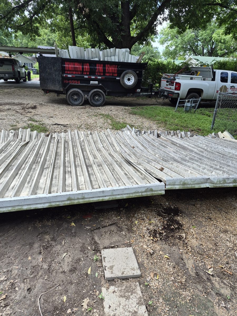 Metal carport panels stacked on the ground beside the loaded trailer