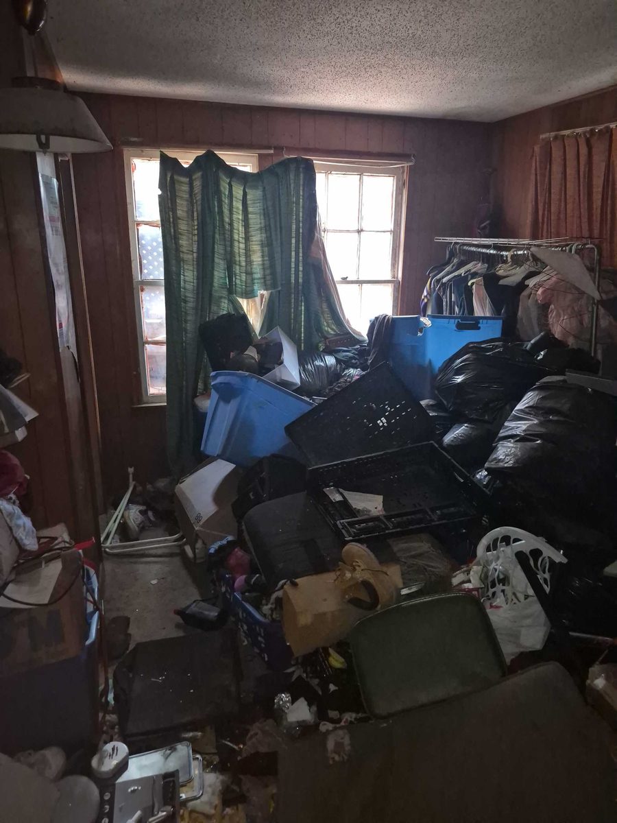 Room packed with furniture, boxes and bags before a full cleanout