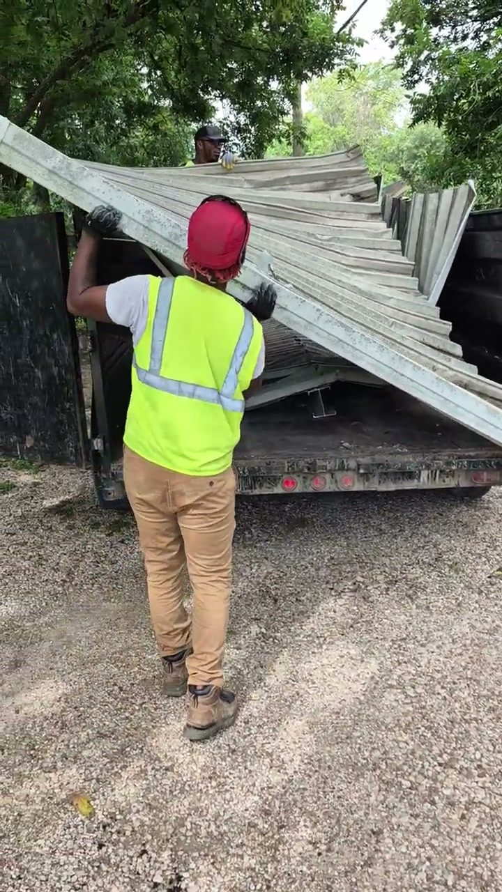 Crew member carrying a metal carport panel to the trailer