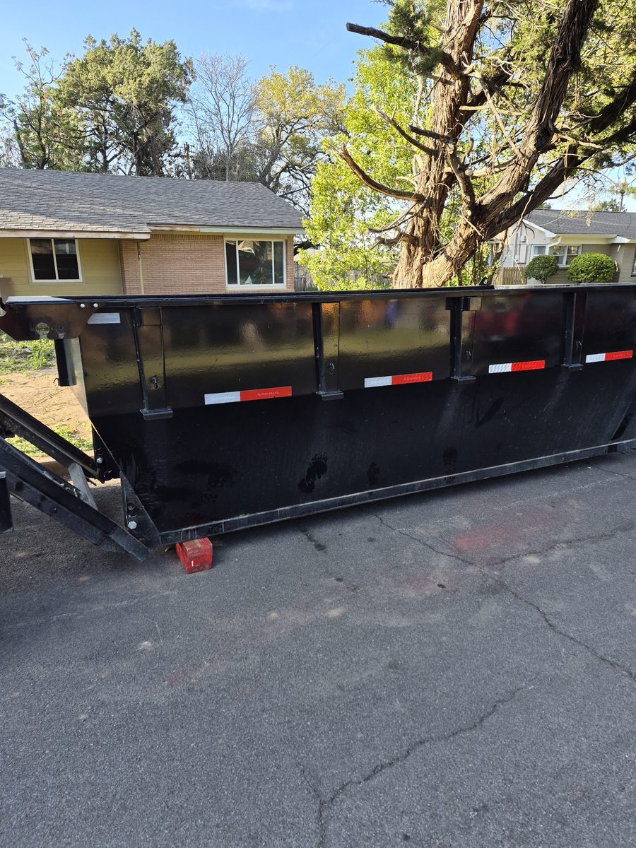 Roll-off dumpster set on a driveway beside a house