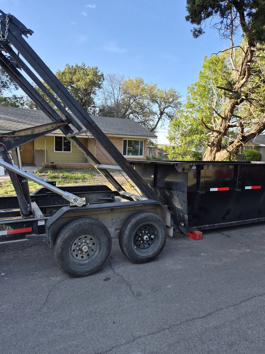 Roll-off dumpster being lowered off the trailer at a home