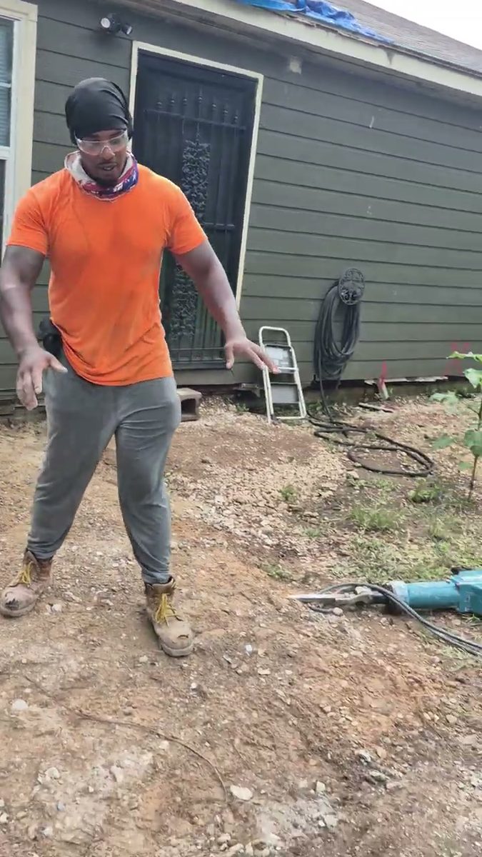 Munachi standing on graded dirt where a concrete slab was removed