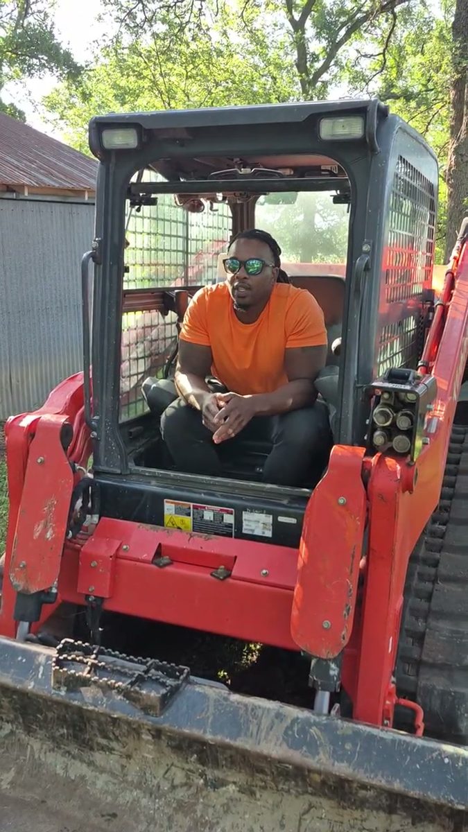 Munachi operating a compact track loader on a lot-clearing job