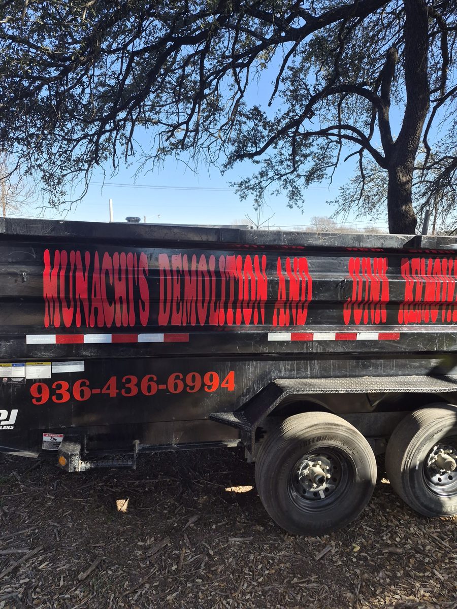 The branded Munachi's dump trailer parked under oak trees